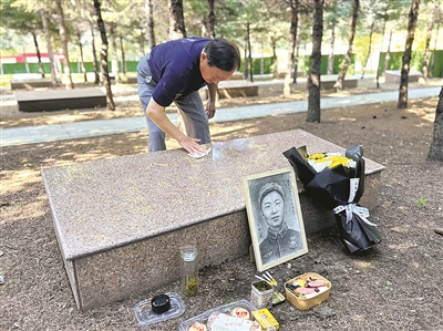 胡继明为父亲擦拭墓碑。刘阳阳摄