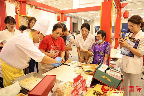 演出前，在天津桂发祥十八街麻花制作技艺非遗体验展台前，泰国民众体验天津麻花制作。人民网记者 杨一摄